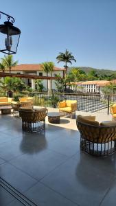 eine Terrasse mit Sofas, Tischen und Stühlen in der Unterkunft Flat da Mata - Resort Quinta Santa Bárbara in Pirenópolis