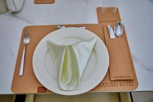 une plaque blanche avec une serviette verte sur une table dans l'établissement Ozinny Signatures Hotel, à Jidu