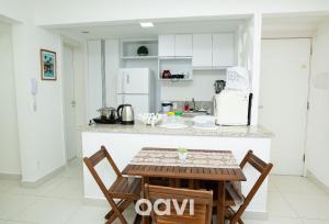 a white kitchen with a table and two chairs at Qavi - Flat Resort Beira Mar Cotovelo #InMare322 in Parnamirim