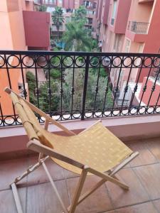 a folding chair on a balcony with a view of a city at Superbe appartement lumineux in Marrakesh