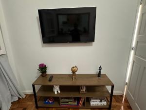 a living room with a tv on a white wall at Casa Palácio de Cristal no centro Histórico de Petrópolis in Petrópolis