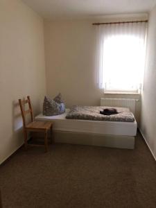 een slaapkamer met een bed, een stoel en een raam bij Haus in Weisen 