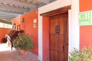 een oranje gebouw met een houten deur en een bord bij Casa Rural El Gaiter in Aguaviva
