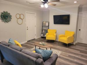 a living room with a couch and two yellow chairs at Cottage in Downtown Houma in Houma