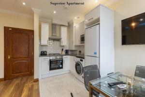 a kitchen with white appliances and a glass table at Stylish Apartment Kensington in London