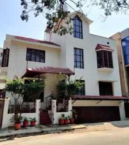 uma casa branca com vasos de plantas em frente em The Rustic Manor - Homestay em Bangalore
