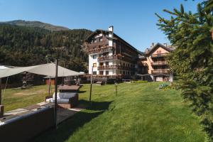 a large building with a grassy yard in front of it at Residence Les Coupoles in Champoluc