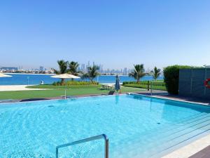 una gran piscina junto a un cuerpo de agua en LUXURY APARTMENT / 2 BR / BRAND NEW / PRIVATE BEACH / THE8 en Dubái