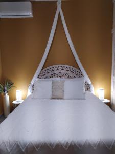 a bedroom with a white bed with two lamps at Villa Créoléna in Anse-Bertrand
