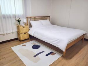 a bedroom with a bed with a white sheets and a rug at Stay Mellow in Seoul