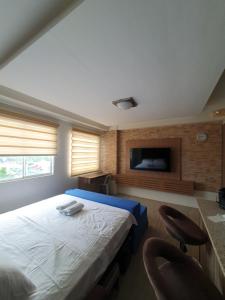 a bedroom with a bed with two chairs and a tv at Amaia Steps Capitol Central N814 in Bacolod