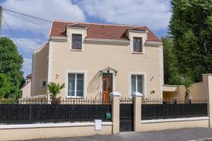 a white house with a black fence at Joli Appartement de vacances in Écouen