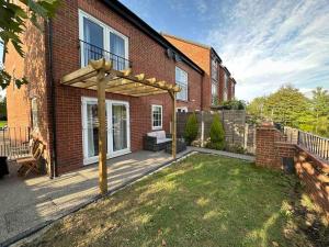 a backyard with a pergola on a brick house at Waterside 4BR Townhouse Stretford, FREE Parking in Manchester
