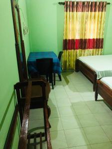 Cette chambre comprend deux lits, une table et une chaise. dans l'établissement River Garden Hotel Anuradhapura, à Anurâdhapura