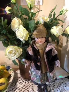 una muñeca está de pie junto a un jarrón de rosas en Castellino di Malborghetto, en Montelupo Fiorentino
