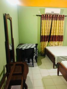 Cette chambre comprend un lit, une table et une chaise. dans l'établissement River Garden Hotel Anuradhapura, à Anurâdhapura