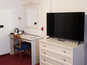 a bedroom with a television on a dresser with a desk at Hotel Negritella in Fai della Paganella