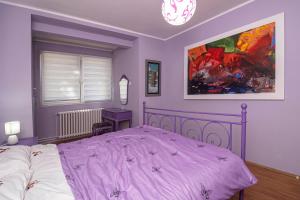 a purple bedroom with a bed and a painting at Q9 in Kragujevac