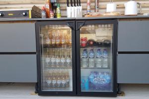 a refrigerator filled with bottles of water and soda at Seaside Escape - Deganwy Beach Cottage - Sea Views & Golf Course Views in Deganwy
