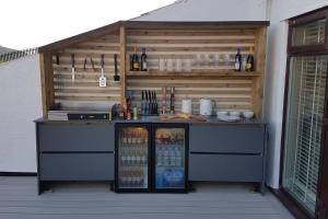 an outdoor bar with a drink cooler and bottles at Seaside Escape - Deganwy Beach Cottage - Sea Views & Golf Course Views in Deganwy