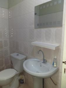 La salle de bains est pourvue de toilettes blanches et d'un lavabo. dans l'établissement KEUR AMINATA, à Dakar
