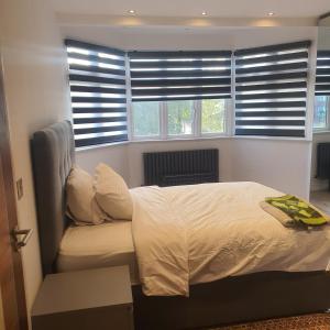 a bedroom with a bed and windows with blinds at 64 Salmon Street in London