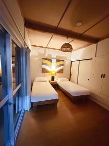 a room with two beds and a lamp in it at Snowood Chalet Hakuba in Hakuba