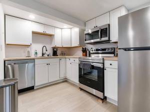 a kitchen with white cabinets and stainless steel appliances at Renovated Hawthorne Retreat in Portland