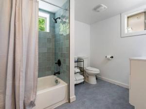 a bathroom with a tub and a toilet and a shower at Renovated Hawthorne Retreat in Portland