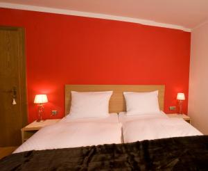 two beds in a room with a red wall at Gästehaus Hochtirol in Vorderlanersbach