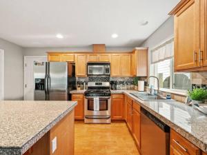 a kitchen with wooden cabinets and stainless steel appliances at Troutdale Treasure - Spacious 3BR, 3 Bath Home near Edgefield in Troutdale +7 photos