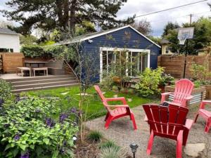 un cortile con sedie rosse e un capanno blu di Alberta Arts with Hot Tub and Yoga Studio a Portland