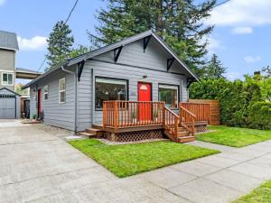 une petite maison avec une terrasse et une porte rouge dans l'établissement Cheerful 2-bedroom Home Near UP and St. Johns, à Portland