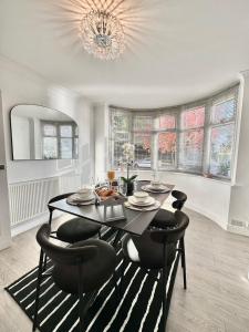 ein Esszimmer mit einem Tisch, Stühlen und einem Kronleuchter in der Unterkunft Luxurious family home in West Midlands in Northfield