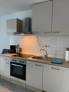 una cocina con armarios blancos y fregadero en SoNi Apartment en Dieburg