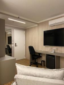 a room with a desk and a chair and a television at Flat Hotel in Sao Paulo
