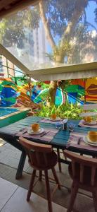 une table avec des tasses, des assiettes et une fresque murale dans l'établissement A Casa Morro do Moreno, à Vila Velha