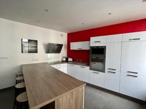 una cocina con armarios blancos y una pared roja en Appartement superbe Rooftop 70m2 Clermont Ferrand, en Clermont-Ferrand