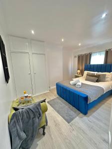a large bedroom with a blue bed and a chair at Luxurious family home in West Midlands in Northfield