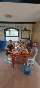 grupa ludzi siedzących przy drewnianym stole w obiekcie Vibe House Arraial w mieście Arraial do Cabo