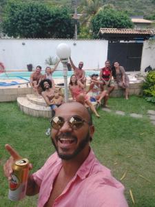 un hombre con una bebida y un grupo de personas en Vibe House Arraial en Arraial do Cabo