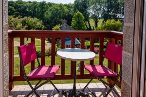 a table and two pink chairs on a balcony at Hostellerie de la Motte jean in Saint-Coulomb