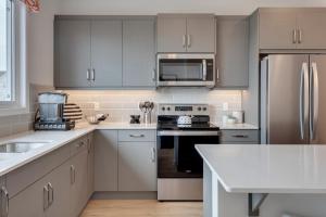 a kitchen with white cabinets and stainless steel appliances at Luxurious Modern Home With King Bed & Office in Calgary