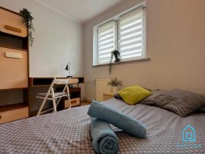 a bedroom with a bed and a desk and a window at Cheerful Room in Gdańsk