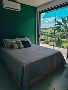 a bedroom with a large bed with a large window at Casa Container com SPA e linda vista para a Serra da Mantiqueira in Bueno Brandão