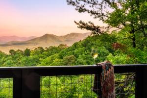 a glass of wine on a balcony with a mountain view at Woodhaven - Private - 3 Suites - Gorgeous Views - 3 Pools - GameRm - HotTub - Lots of Bears in Gatlinburg