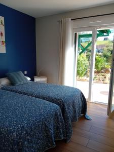 a bedroom with a bed with a blue bedspread and a window at ATALOZTI Maison d'hôtes ST JEAN PIED DE PORT in Ascarat