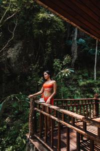 a woman in an orange dress standing on a bridge at The Vatika Resort and Spa in Ao Nang Beach