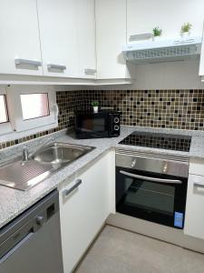 eine Küche mit einer Spüle und einer Mikrowelle in der Unterkunft Junto Al Mar III in La Manga del Mar Menor