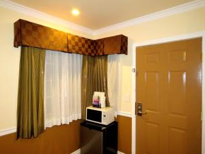 a room with a door and a microwave next to a window at La Bonita Inn Motel in Long Beach